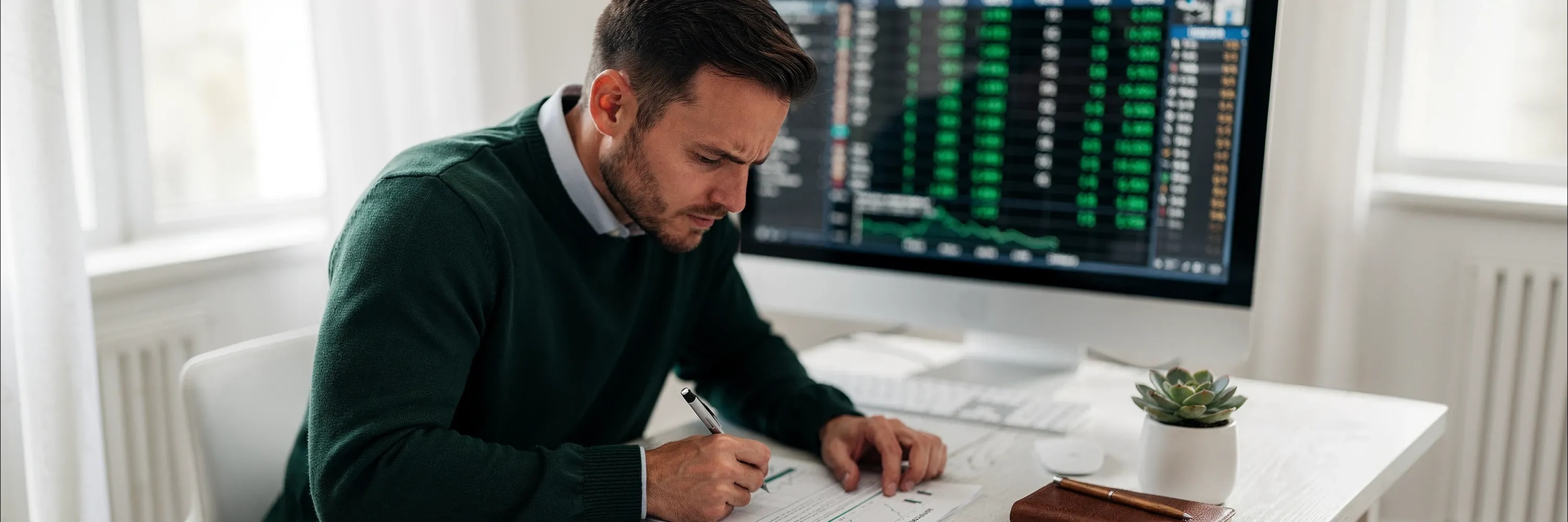 Investor reviewing stock market charts and financial data while analyzing investment performance at a desk with a trading screen